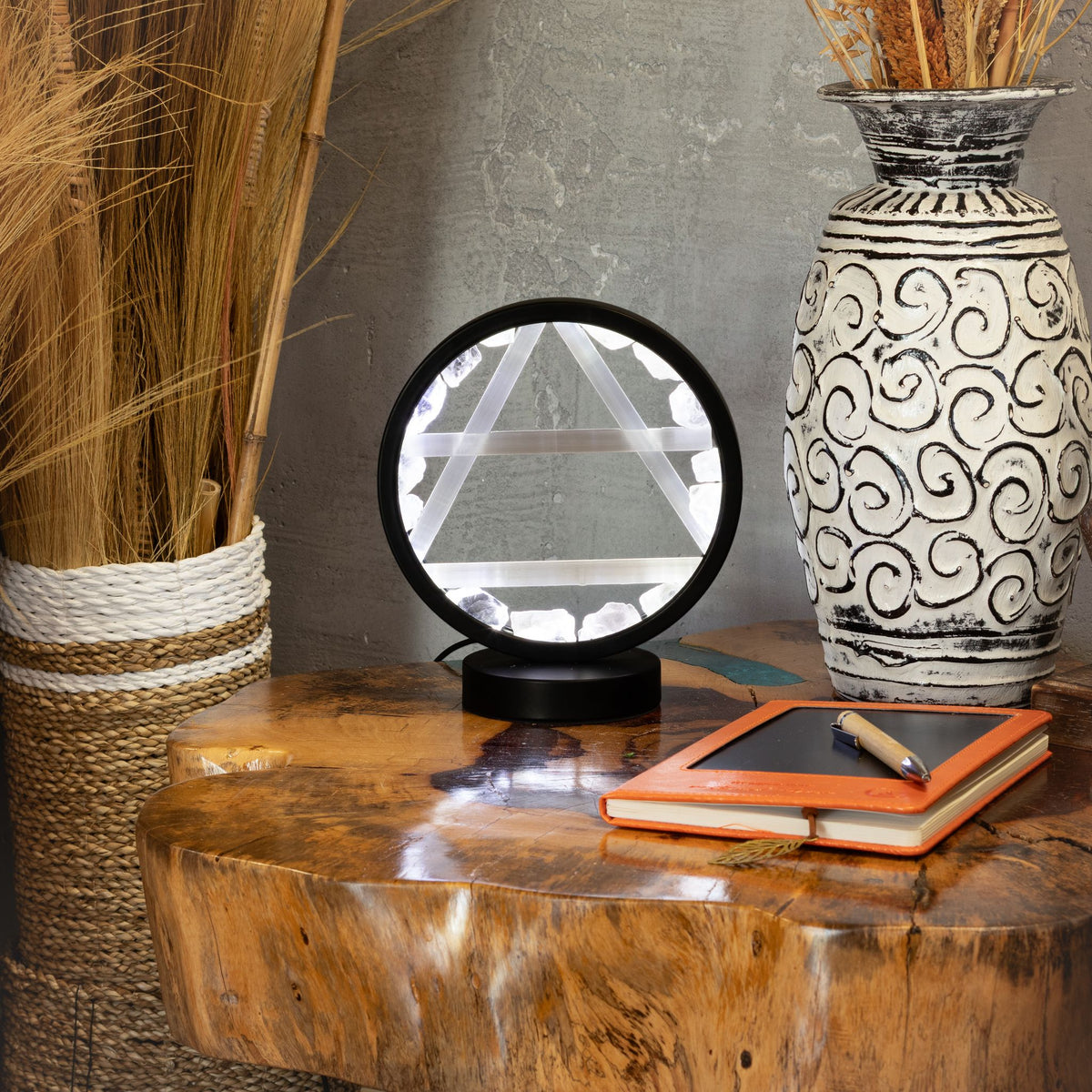 Air gemstone halo lamp with clear quartz and selenite displayed in a home setting with a teak table under and r
grass in vases next to it